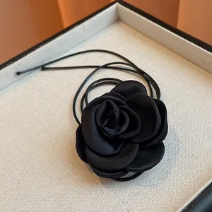 Close-up of a stylish black fabric rose necklace with a sleek braided leather-look cord.