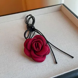 Detailed macro view of a red fabric rose choker with elegant black leather cord ties.