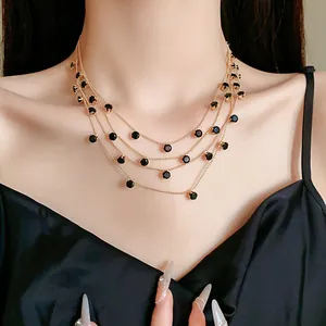 Gros plan d'un collier doré multicouche avec des zircons noirs ronds sur le cou du mannequin