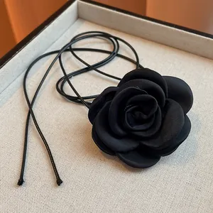 Macro view of a handmade black fabric rose pendant necklace with a sleek leather cord