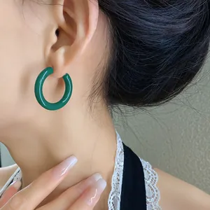 Primo piano di una modella che indossa orecchini a cerchio in acrilico verde