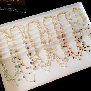 Colliers dorés multicouches élégants avec zircons circulaires colorés dans un plateau
