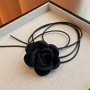 Close-up detail of a handmade black fabric rose choker with multi-layer leather cords.