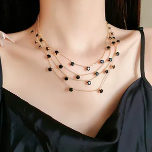 Détail macro d'un collier chaîne doré multicouche élégant avec zircons ronds noirs