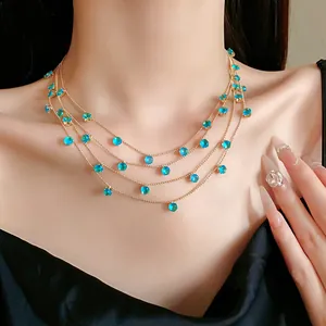 Vue détaillée d'un élégant collier doré à plusieurs rangs avec des zircons bleus.