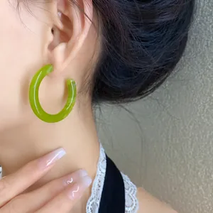 Primo piano di un orecchino a cerchio a forma di C in acrilico verde lime su un modello