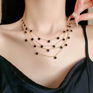 Détail d'un collier multicouche doré avec des pierres de zircon noir rondes de style vintage.