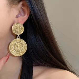 Detailed view of exaggerated golden circular earrings with lion head motif on model