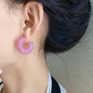 Primo piano di orecchini a cerchio in acrilico rosa a forma di C indossati da una modella