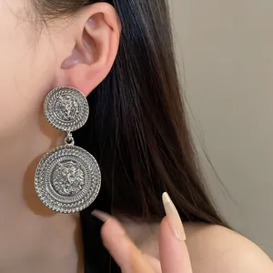 Detailed macro view of silver-toned geometric lion head drop earrings worn by a model.