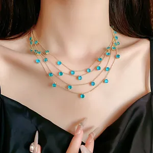 Vue détaillée d'un collier doré à quatre rangs avec des pierres de zircon rondes bleues.