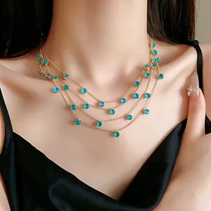 Vue détaillée du collier multi-rangs doré avec zircons bleus sur un mannequin.
