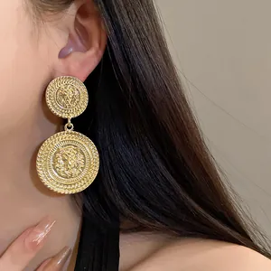 Close-up of golden circular drop earrings featuring embossed lion head design