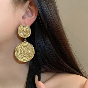 Detailed macro shot of vintage gold lion head geometric earrings worn by a model.