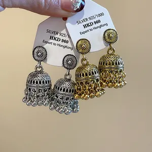 Primo piano di orecchini Jhumka bohémien in argento e oro con intagli e nappe pendenti