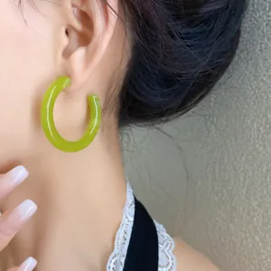 Primo piano di orecchini a cerchio a C in acrilico verde lime su una modella