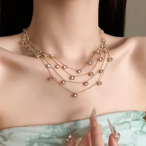 Gros plan d'un collier multicouche en or avec des pierres de zircon rose sur le cou.