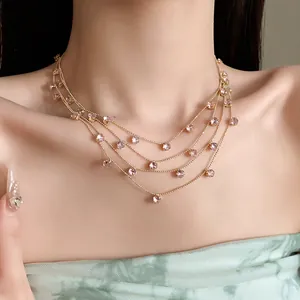 Gros plan d'un collier doré multicouche avec des breloques rondes en zircon rose