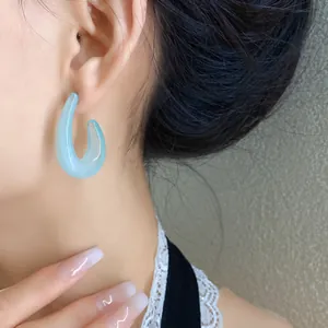 Primo piano di eleganti orecchini a cerchio a C in acrilico azzurro su una modella