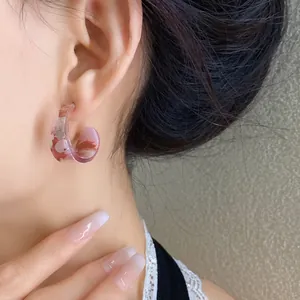 Dettaglio ravvicinato di orecchini a cerchio in acrilico rosa su una bella modella