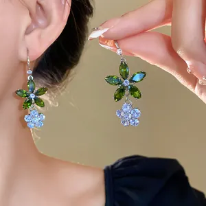 Nahaufnahme eleganter Blumentropfenohrringe mit grünen und weißen Zirkonia-Steinen