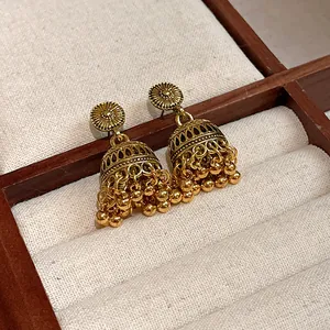 Primo piano di orecchini Jhumka dorati in stile bohémien con incisioni dettagliate