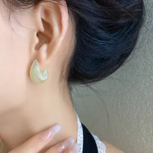 Vista dettagliata di eleganti orecchini minimalisti in acrilico marmorizzato verde a C
