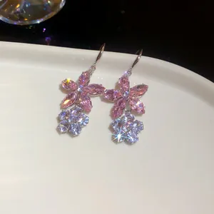 Detailansicht der funkelnden rosa und weißen Zirkon-Blumen-Ohrhänger auf einem Teller.
