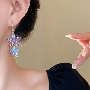 Nahaufnahme von funkelnden lila und blauen Zirkon-Blumenohrringen an einem Model