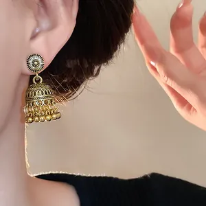Dettaglio degli orecchini jhumka bohémien dorati con nappe di perline intagliate