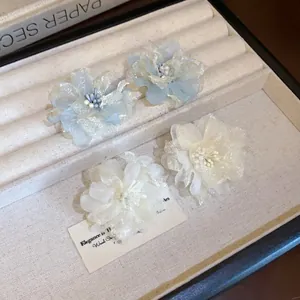 Primo piano di orecchini a fiore in rete fatata con delicati centri di stami in azzurro.