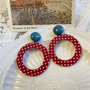 Orecchini vintage a pois rossi con perni blu su un piatto decorativo bianco elegante
