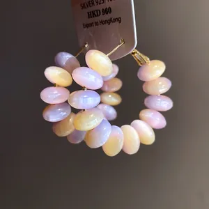 Close-up of pastel iridescent resin bead hoop earrings with silver needles