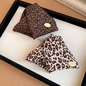 Macro view of stylish leopard print fabric triangular hair clips with small gold brand tags