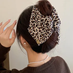 Detailed macro view of a leopard print fabric bow shark hair clip on a classic bun hairstyle.