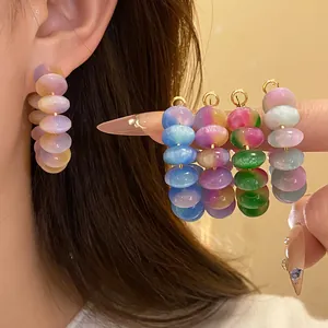 Close-up of colorful resin bead hoop earrings and studs in various gradient shades.