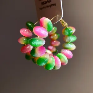 Close-up of colorful resin bead hoop earrings with vibrant pink and green tones.