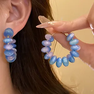 Close-up of blue and purple cat-eye resin bead hoop earrings with silver pins