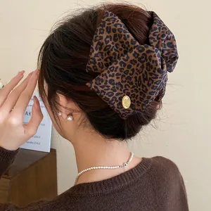Detailed view of a stylish leopard print bow hair clip on an elegant bun hairstyle.