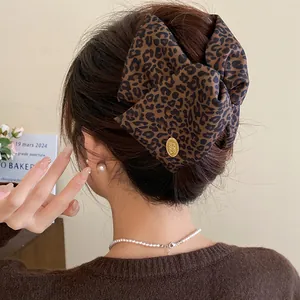 Detailed view of a leopard print fabric hair clip used in a stylish bun hairstyle.