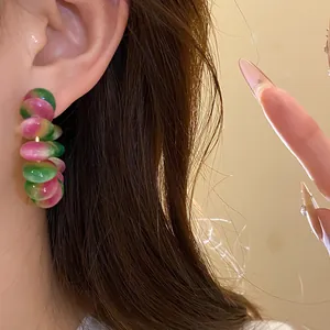 Close-up detail of stylish pink and green resin disc hoop earrings worn by a model