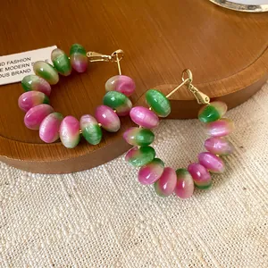 Macro detail of fashionable pink and green gradient resin hoop earrings with silver pins