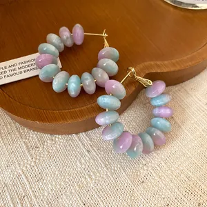 Close-up of sweet forest style round resin hoop earrings in pastel pink and blue colors