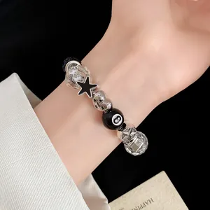 Close-up of a stylish black and silver beaded bracelet with heart and star charms on a wrist.