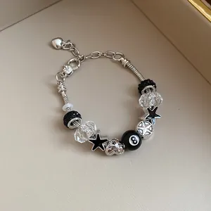 Close-up detail of a silver snake chain bracelet with black star charms and 8-ball bead