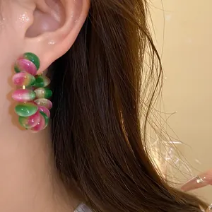 Close-up macro detail of fashionable green and pink gradient resin hoop earring worn on ear