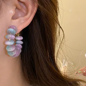 Elegant round resin hoop earrings with iridescent purple and blue beads worn on ear