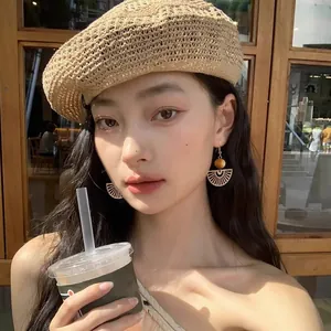 Close-up of bohemian style wooden bead fan-shaped drop earrings worn by a model