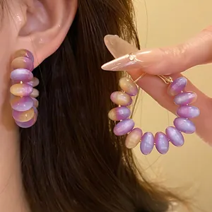 Macro view showing the texture of colorful resin bead hoop earrings on the ear