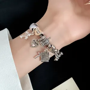 Macro view of silver charm bracelet with heart pendants and engraved message on model wrist
